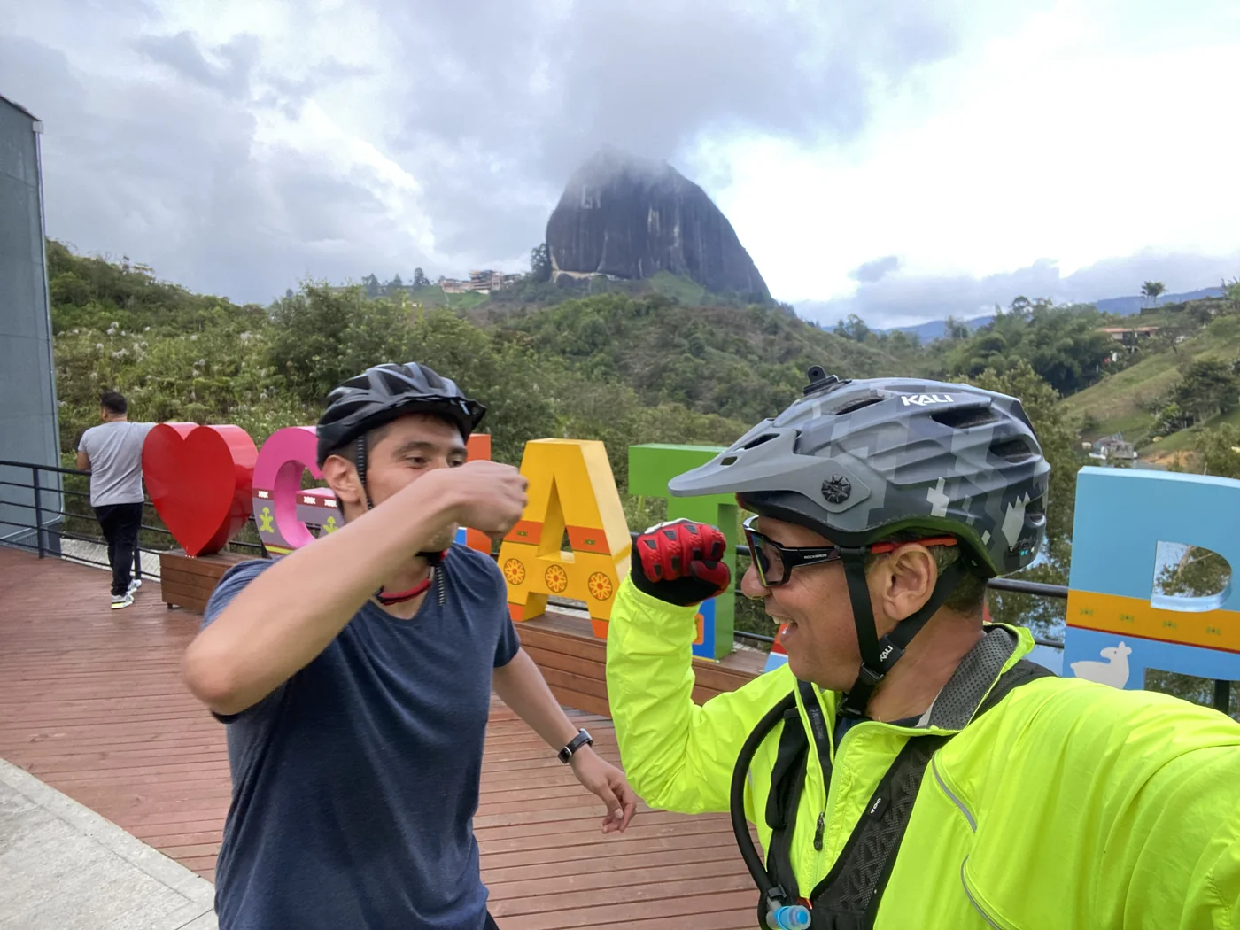 Free morning bike ride group fist-bumping at the Guatapé sign with La Piedra del Peñol