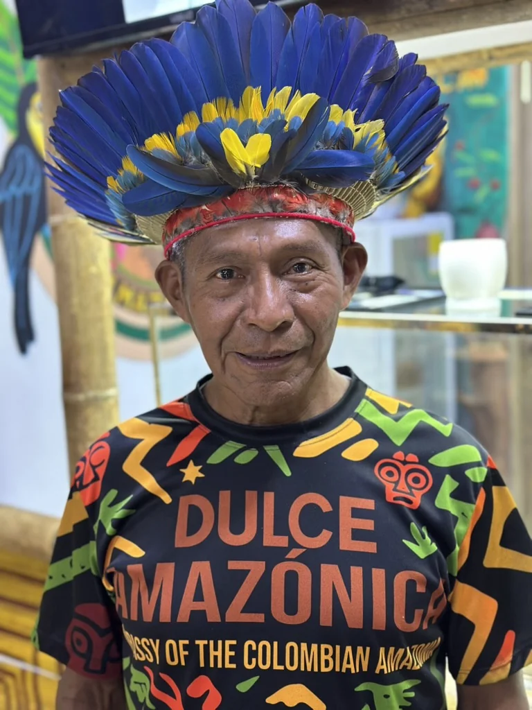 Indigenous ambassador wearing blue and yellow macaw feather headdress and Dulce Amazónica jersey, Guatapé