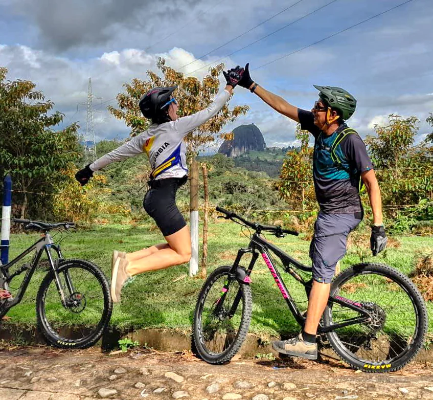 Cyclists celebrating with La Piedra del Peñol in the background, Guatapé