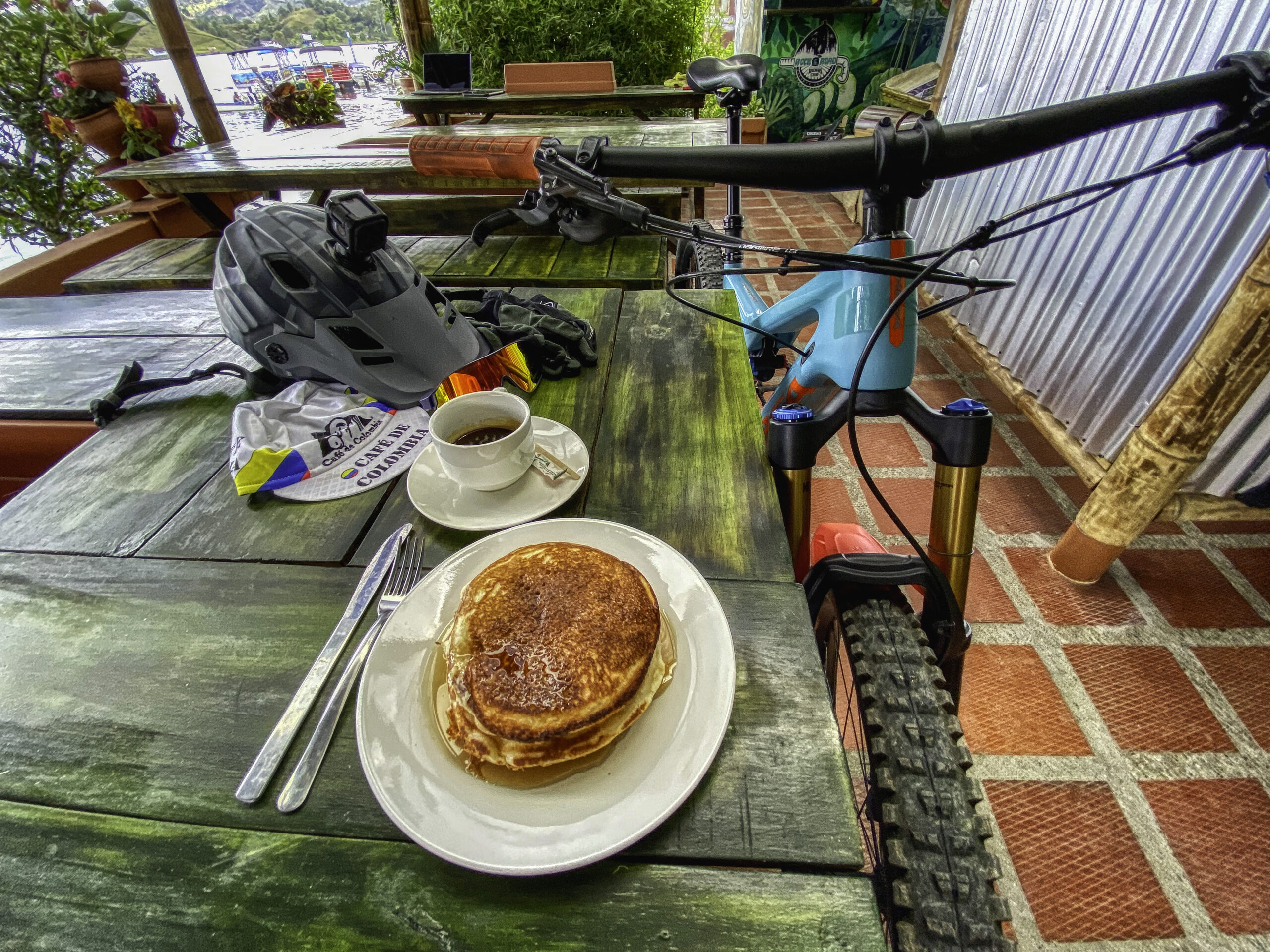 Mountain bike and helmet on the table at Casa de Ciclistas with pancakes and coffee, Guatapé